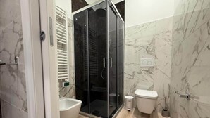Un baño moderno con ducha de vidrio, un lavabo blanco y un inodoro.