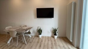 A modern meeting room with a large table, white chairs, a mounted TV, and two potted plants. - Apartment Basilica of Sant'Ambrogio (Milan)