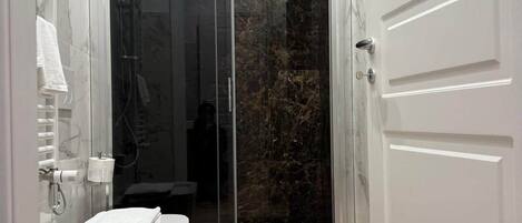 Een moderne badkamer met een douchecabine van glas, een wit wastafelmeubel en een toilet.