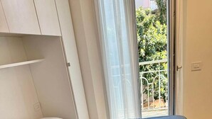 Une chambre à coucher avec un lit, une fenêtre avec des rideaux et une vue sur la verdure à l’extérieur.