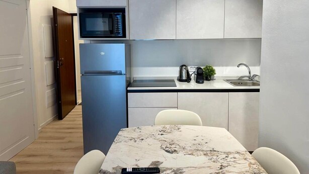 Une cuisine compacte équipée d’un four à micro-ondes, d’un réfrigérateur, d’un évier et d’un petit coin repas avec une table et des chaises en marbre.
