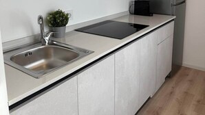 A modern kitchen with a stainless steel sink, a black induction cooktop, and a built-in microwave. - Milan Cathedral Apartment (Milan)