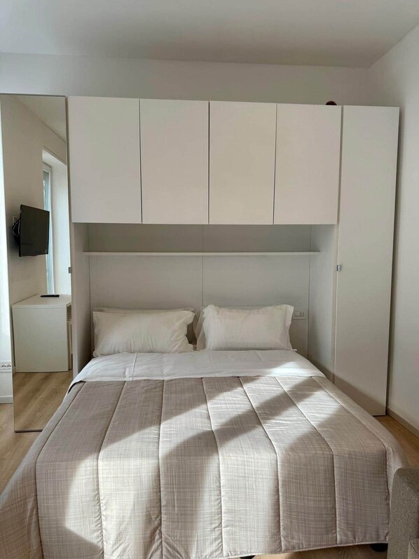 Een slaapkamer met een bed, een televisie en een kledingkast.