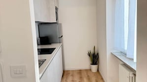 A compact kitchen with white cabinetry, a built-in stove, and a small potted plant. - Milan Cathedral Apartment (Milan)