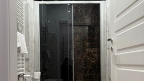 A modern bathroom with a glass shower enclosure, a white bathtub, and a sink. - Penthouse Apartment in Sforza Castle (Milan)