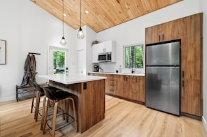 Una cocina moderna con armarios de madera, refrigerador de acero inoxidable y encimera blanca.