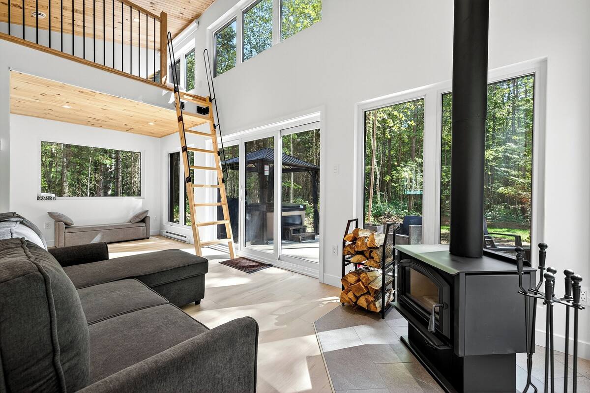 Ein modernes Wohnzimmer mit Erker, großen Fenstern, einem Kamin und einer Treppe.