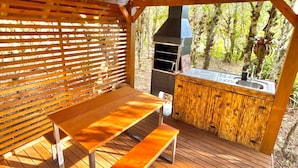 An outdoor wooden deck with a picnic table and a barbecue grill.