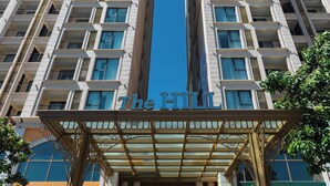 Un hotel moderno de gran altura con entrada central, varios balcones y cielo despejado.