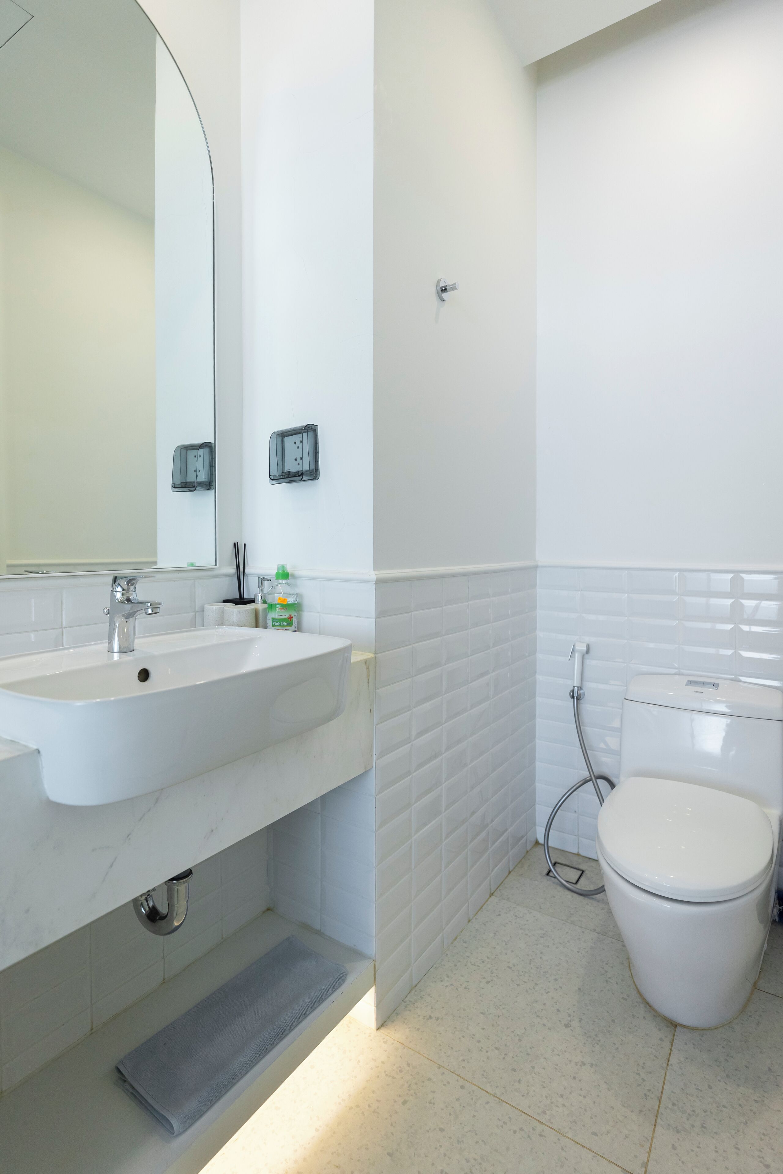 Un baño moderno con lavamanos, espejo y inodoro blancos.