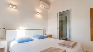 A bedroom with a bed, bedside table, and a glass shower door.