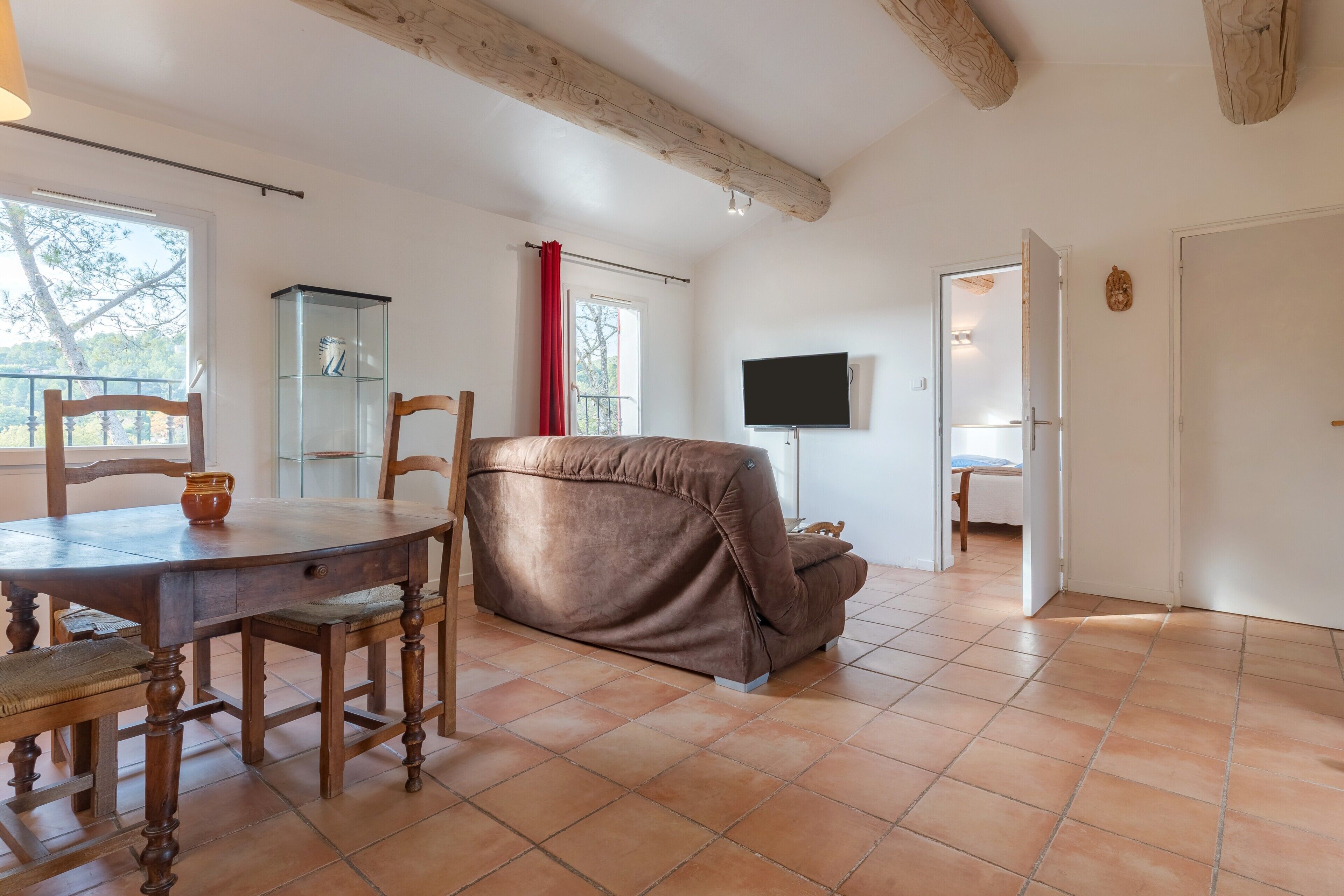 Ein Zimmer mit Esstisch, Stühlen, einer Couch, einem Fernseher und einem Schrank.