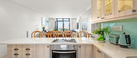 Cocina moderna con una isla central, horno empotrado y un comedor con sillas.