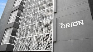 A building facade with a geometric patterned facade and the name "THE ORION" in large letters.