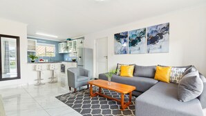 A modern living room with a grey sofa, a wooden coffee table, and a grey patterned rug. - Big Bay Beach Club 137 (Blouberg)