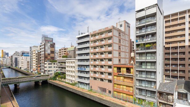 A multi-story building with a river running alongside it. - 5-minute walk from Nihonbashi Station/ Luggage storage available in front of the building/ Families are welcome/ Within walking distance of Kuromon Market, Shinsaibashi, and Namba/ 24-hour supermarket nearby/ Fixed Wi-Fi available (Osaka City)