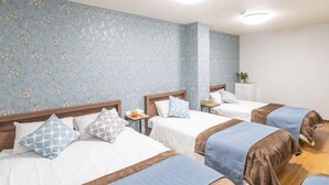 A hotel room with three beds, floral wallpaper, and a small table with a plant. - 5-minute walk from Nihonbashi Station/ Luggage storage available in front of the building/ Families are welcome/ Within walking distance of Kuromon Market, Shinsaibashi, and Namba/ 24-hour supermarket nearby/ Fixed Wi-Fi available (Osaka City)
