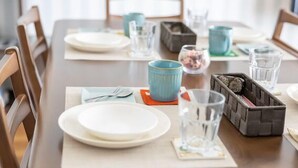 A dining table set with plates, cutlery, and glassware, with chairs around it. - 5-minute walk from Nihonbashi Station/ Luggage storage available in front of the building/ Families are welcome/ Within walking distance of Kuromon Market, Shinsaibashi, and Namba/ 24-hour supermarket nearby/ Fixed Wi-Fi available (Osaka City)