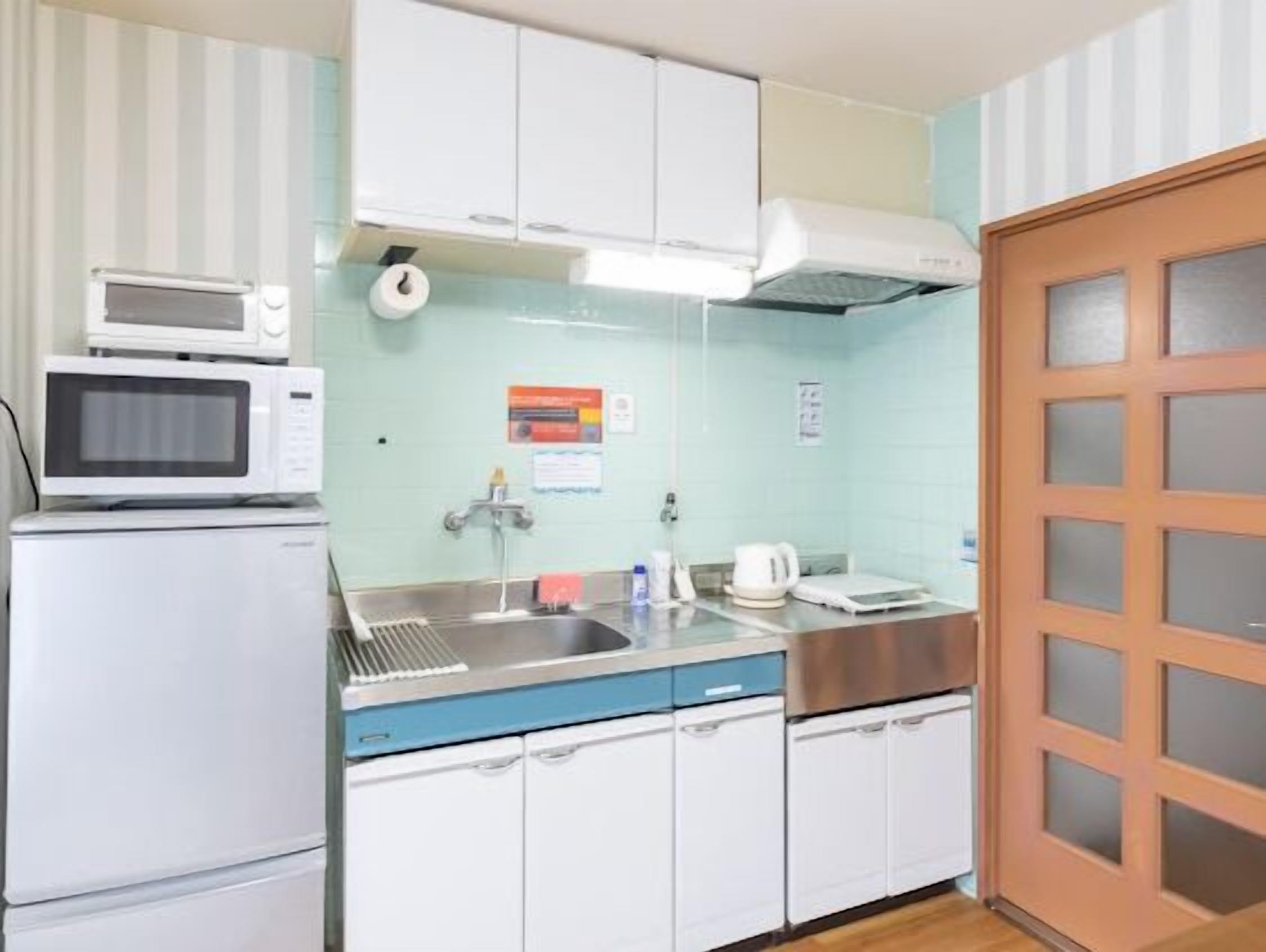 A compact kitchen with a microwave, sink, and stainless steel appliances.
