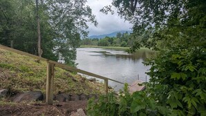 A wooden staircase leading down to a river, surrounded by greenery and trees. - Condo with Backyard Oasis on Ausable River (Wilmington)