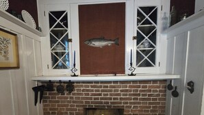 Una chimenea con revestimiento de ladrillo, una decoración de pez sobre la repisa y un estante encima con varios objetos.