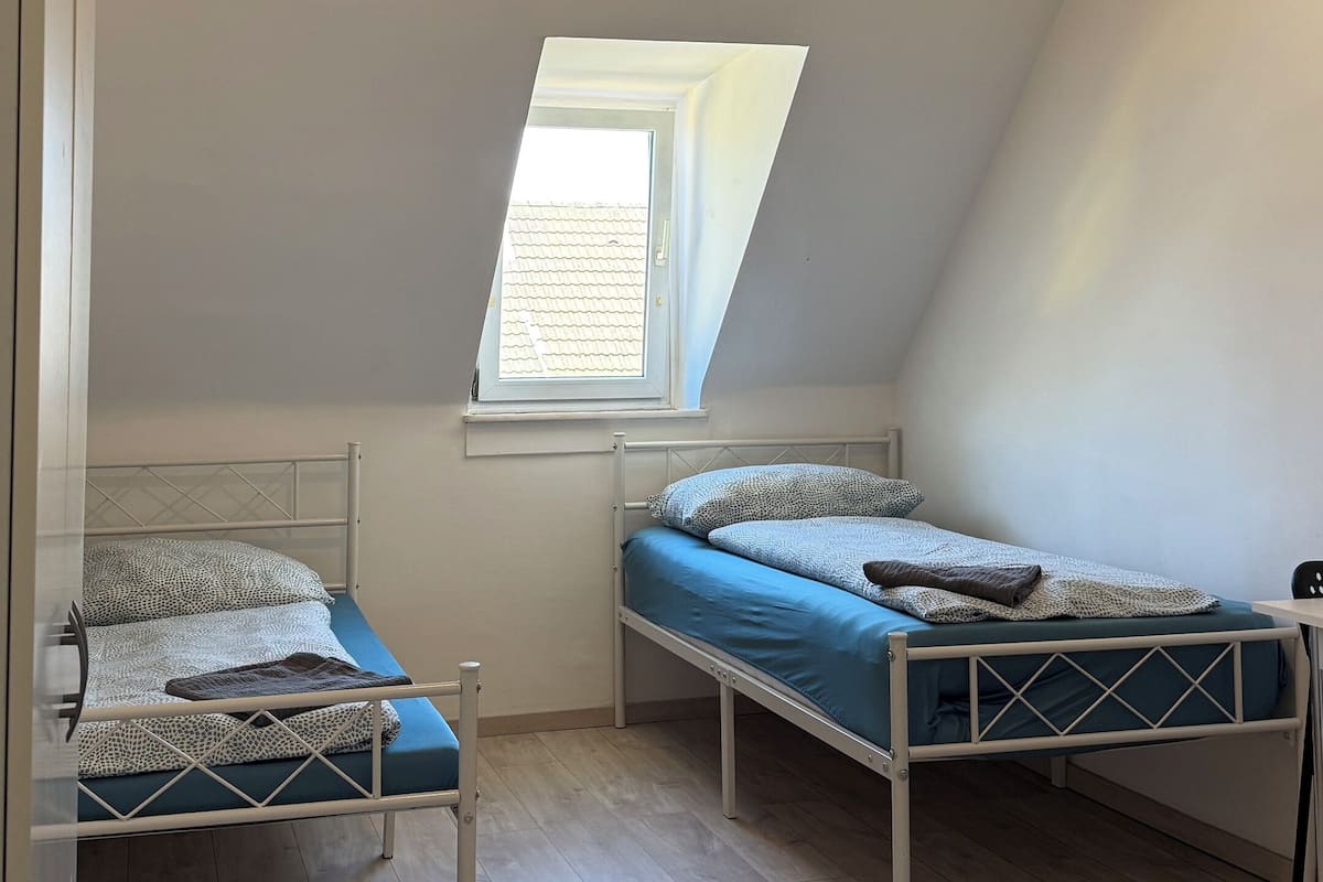 A small, single-room apartment with two bunk beds, a skylight, and a white ceiling.