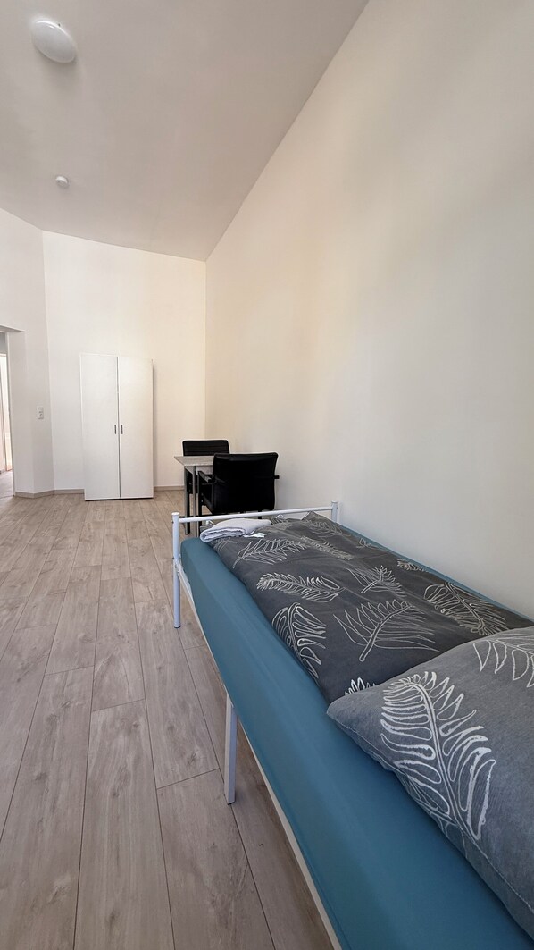 A room with a bed, a desk, and a wardrobe.