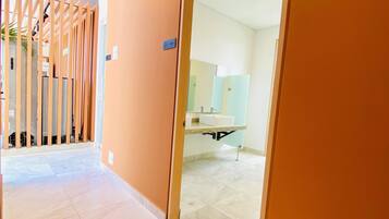 A corridor with a tiled floor leading to a room with a sink and mirror.
