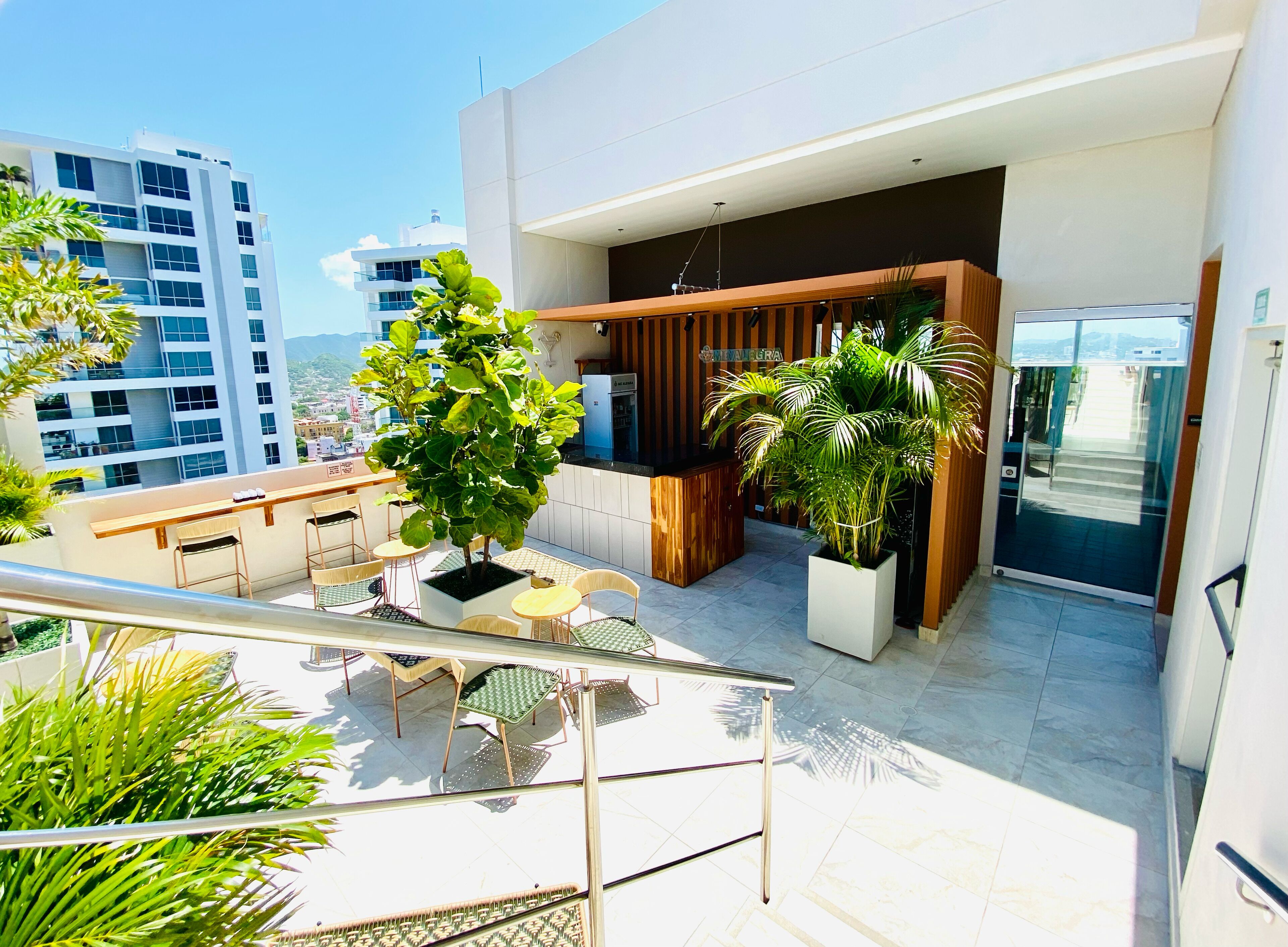 A modern outdoor balcony with a seating area, potted plants, and a view of the cityscape.
