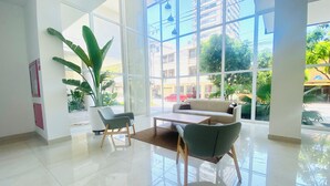 Un hall d’entrée spacieux agrémenté d’une grande plante en pot, d’un canapé et d’une table basse.