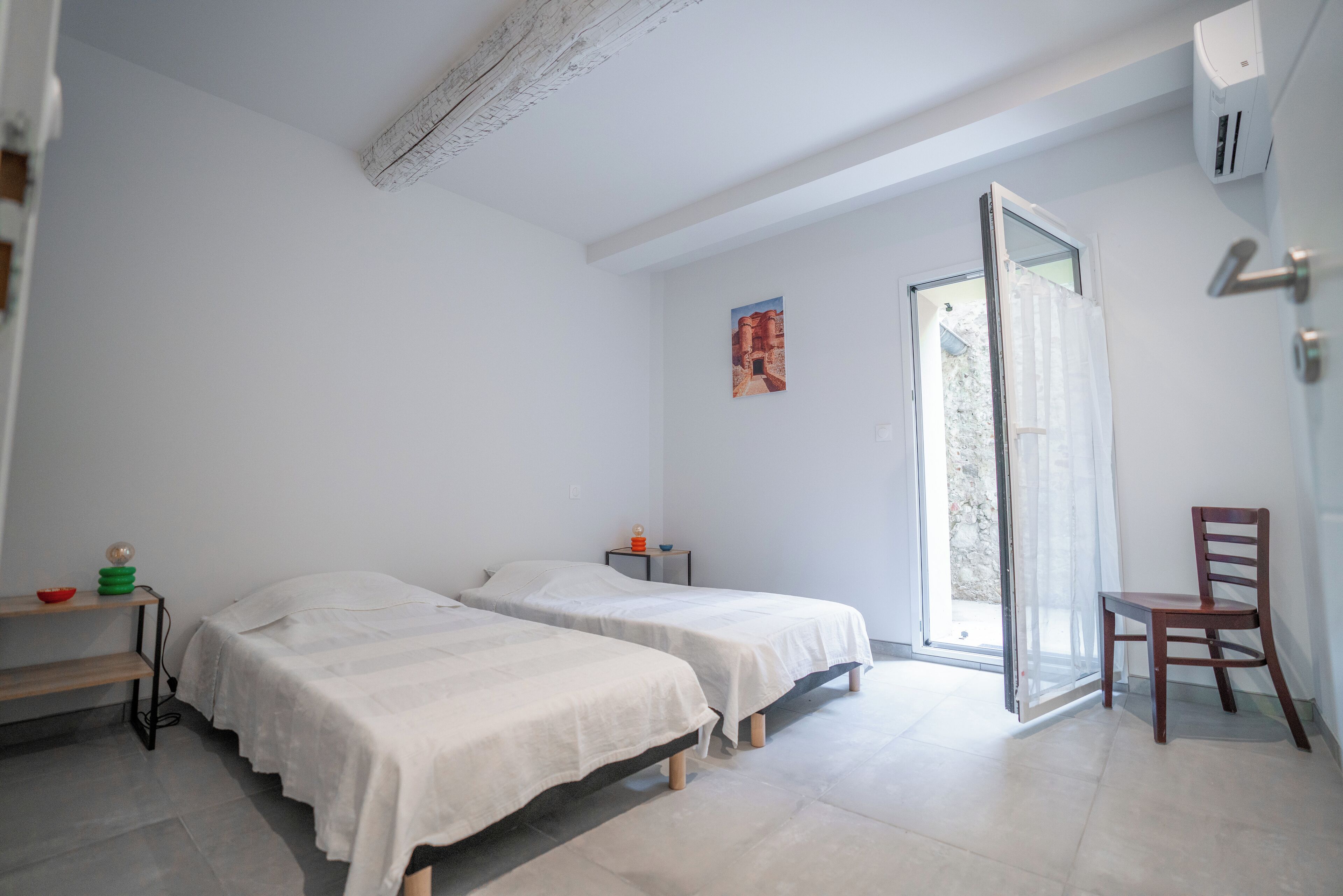 Une chambre avec deux lits, une chaise, une petite table et une fenêtre donnant sur un beau paysage.
