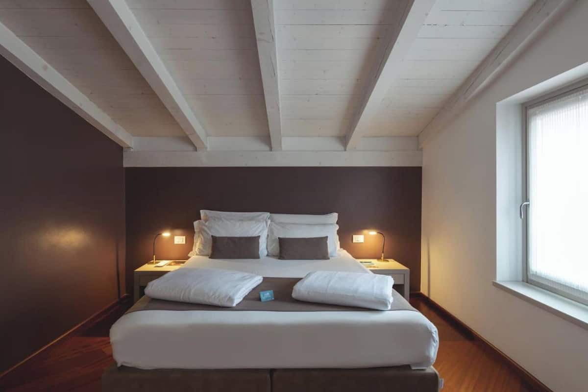 A bedroom with a large bed, two bedside tables, and a window.