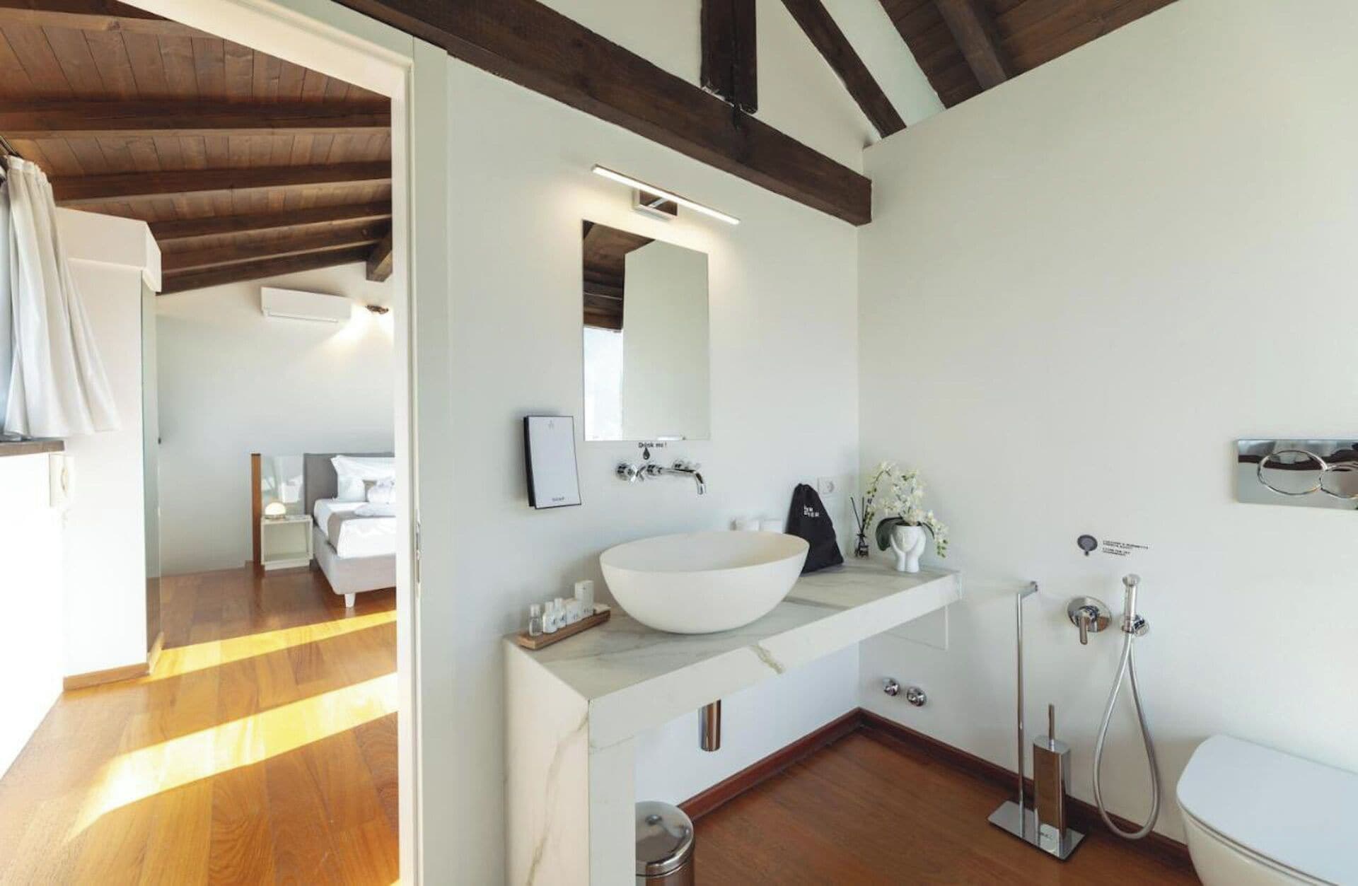 A modern bathroom with a large white sink, a mirror, and a shower.