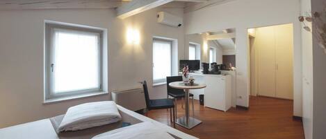 A hotel room with two beds, a small kitchenette, a dining area, and a bathroom.