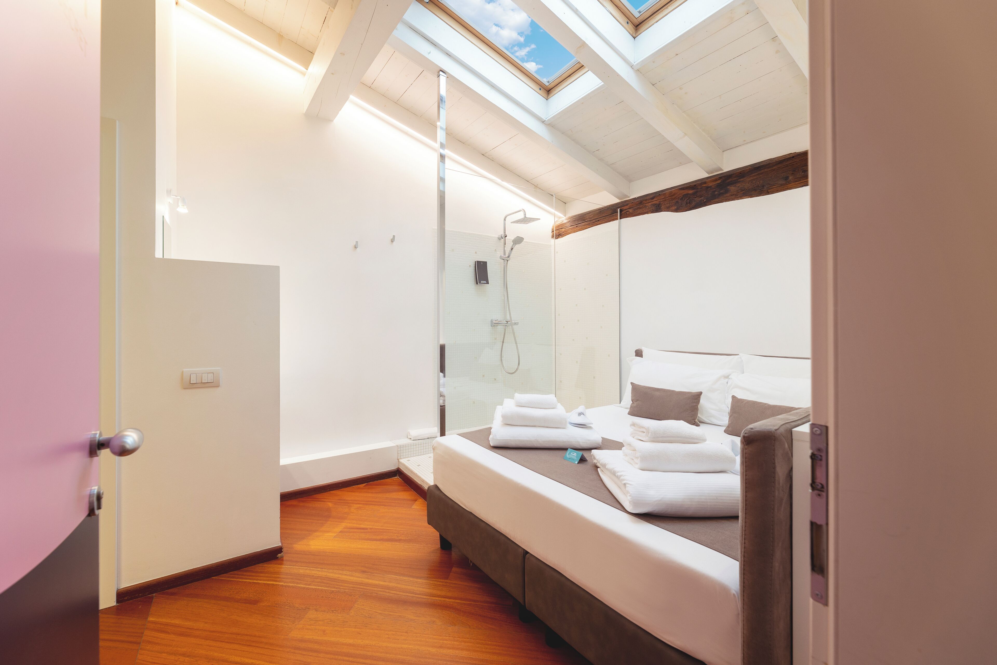 Une chambre à coucher moderne avec une lucarne, une douche et un lit parfaitement fait.