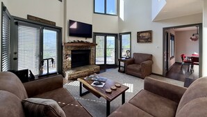 Un salón amplio con chimenea, asientos cómodos y ventanas grandes.