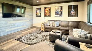 Una sala de estar moderna con un sofá modular, un televisor de pantalla plana y carteles de películas en la pared.