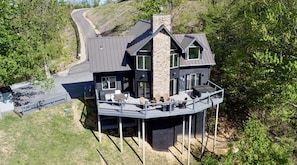 A modern house with a balcony, a stone chimney, and a paved driveway. - Dayna`s Star Gazer Hot Tub (Gatlinburg)