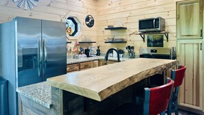 Une cuisine avec des murs en bois, un réfrigérateur en acier inoxydable, un four à micro-ondes et une table à manger en bois, assortie de chaises rouges.