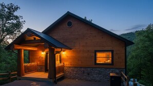 Une cabane en bois dotée d’un porche, de fondations en pierre et d’une allée gravillonnée.