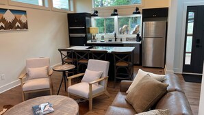 Una cocina moderna con una isla central, un comedor con sillas, un sofá y una mesa de centro.