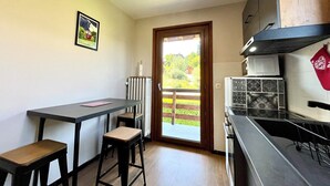 A small kitchen with a table and two stools, a radiator, and a view of the outside.