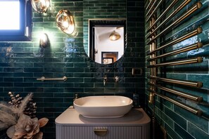 Un baño con un lavamanos ovalado grande, un espejo y una pared con azulejos verdes.