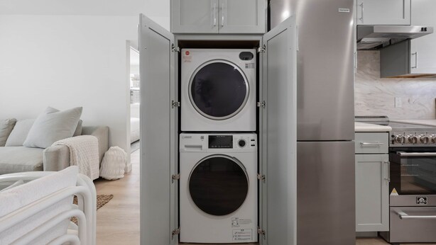 Cocina compacta con lavadora y secadora integradas, refrigerador de acero inoxidable y estufa a gas.