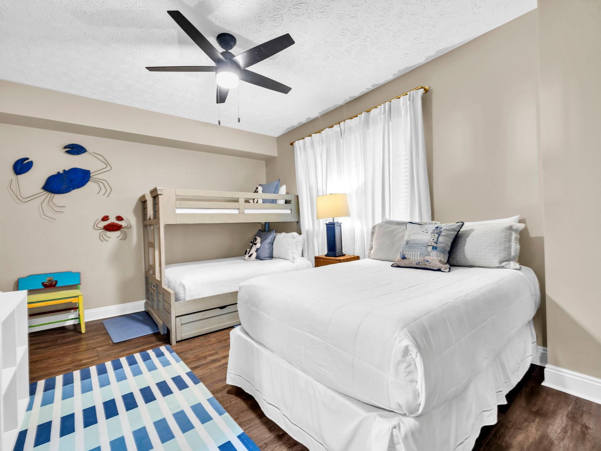 A bedroom with a bunk bed, a single bed, a ceiling fan, and a rug.