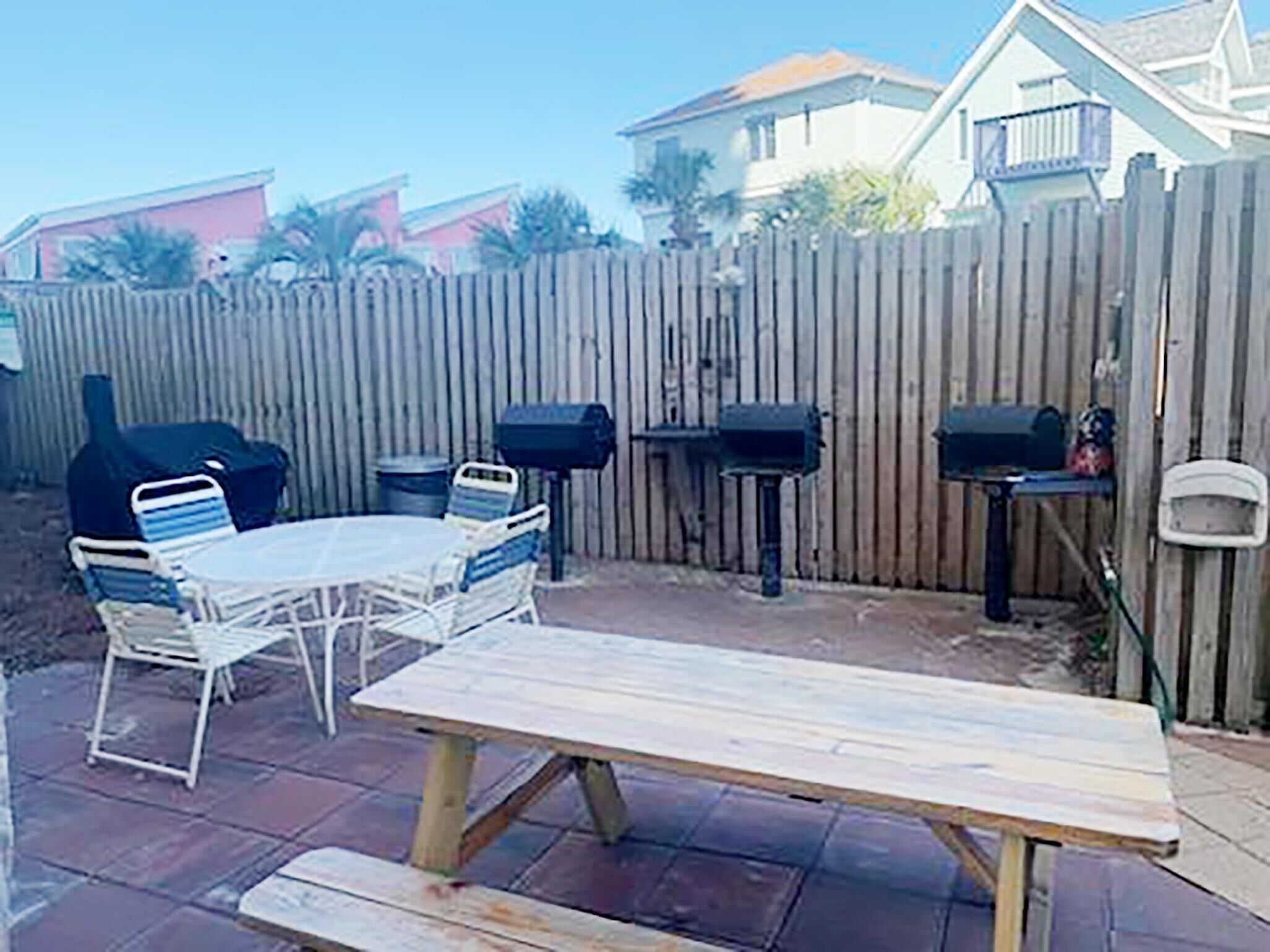 Ein Garten mit einem Holztisch und -stühlen, einem Grill und zwei schwarzen Briefkästen.