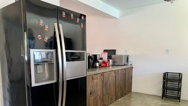 Una cocina con un refrigerador negro, armarios de madera, una cafetera y un estante negro.