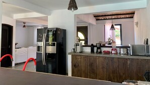 Una cocina compacta con un refrigerador negro, una encimera de madera, un microondas y una cafetera.