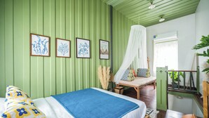 Une chambre à coucher avec un lit, un banc, une fenêtre et des tableaux encadrés accrochés au mur.