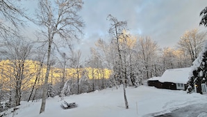 Un paysage enneigé avec une cabane en bois et un banc au premier plan.